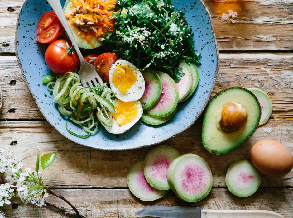 tomatoes, avocado, eggs, cucumber, and zucchini on a blue plate