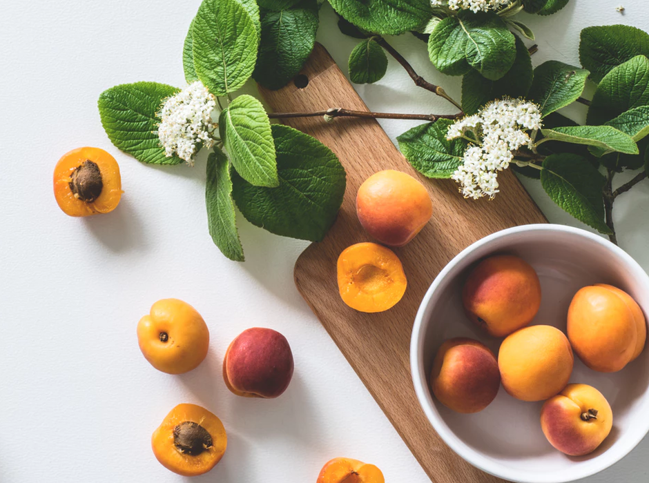 peaches in a bowl and on the counter with white flowers beside them
